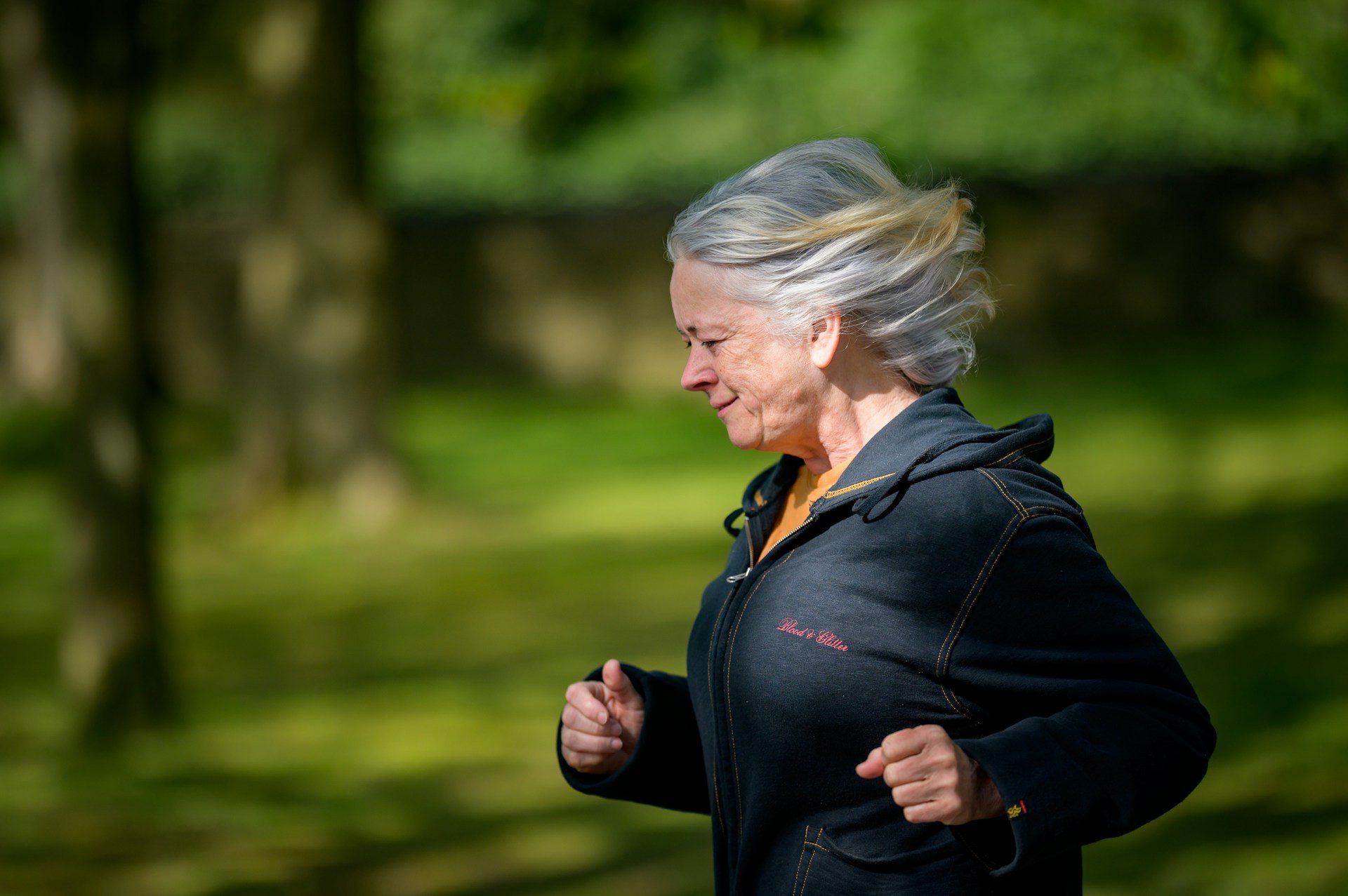 A woman running in a park with trees in the background.